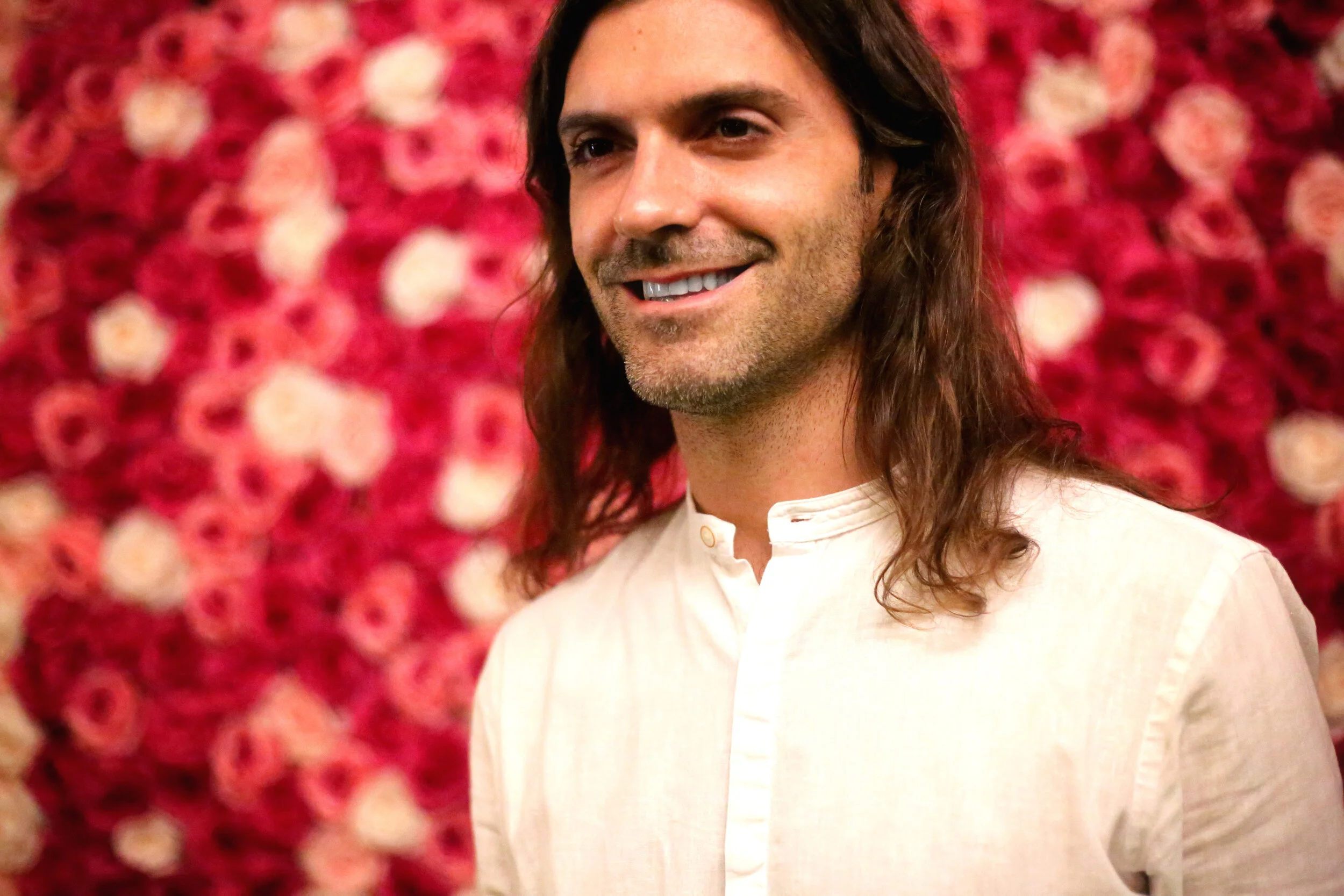 Daniel Bellone smiling in front of a wall of roses